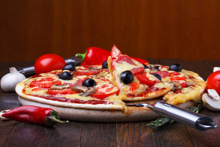 Baked hot pizza with one slice on lifterの写真素材