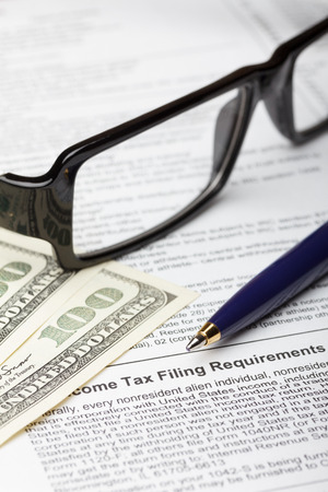 Tax form with pen for fill, dollar bills and glassesの写真素材