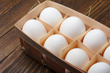 Eggs in a wooden tray on tableの写真素材