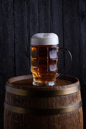 Beer glass on the top of old beer barrelの写真素材