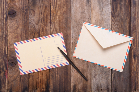 Postcard with fountain pen end envelope on old wooden table