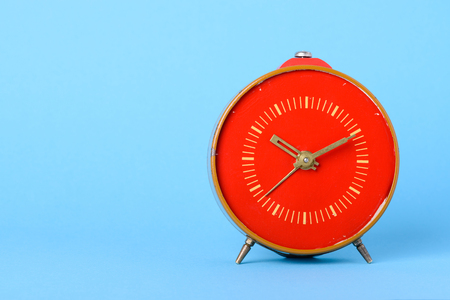 Red retro clock on blue background with copy spaceの写真素材