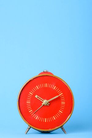 Retro old red clock on blue background with copy spaceの写真素材