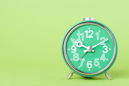 Old retro clock on green background with copy spaceの写真素材