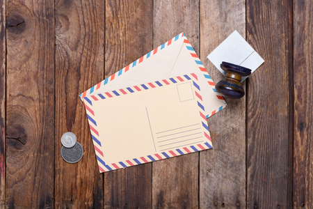 Post card with envelope and old stamp with coins on grunge wooden tableの写真素材