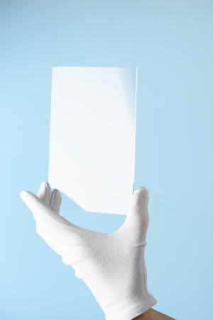 New features of glass or plastic research, hand in glove holding rectangular piece of transparent materialの写真素材