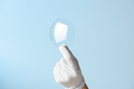 New features glass or plastic research, hand in glove holding circle piece of transparent materialの写真素材