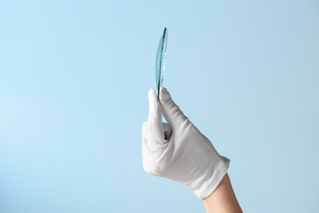 New features of glass research, hand in glove holding circle piece of transparent materialの写真素材