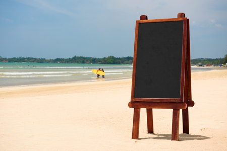 Blank black wooden chalkboard stand in sand on tropical beachの写真素材