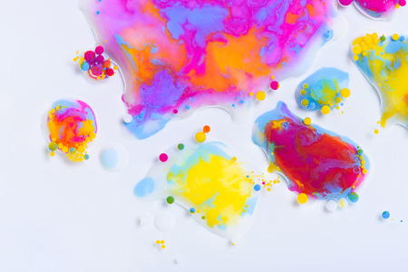 Colorful paint drops mixed in liquid on white backgroundの写真素材