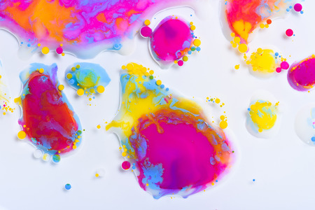 Colorful paint drops mixed in liquid on white backgroundの写真素材