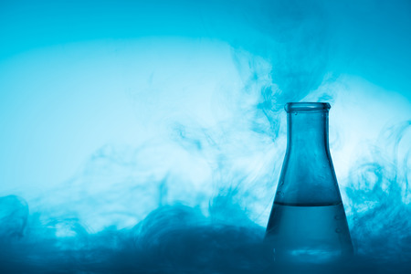 Chemical glass test tube with liquid and steam or smoke backlight on blue background with copy spaceの写真素材