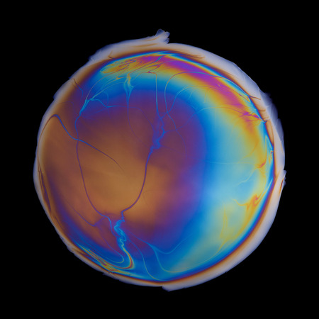 Vivid multicolored circle created by iridescent oil spill  film isolated on black backgroundの写真素材