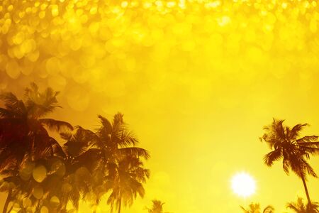 Palm trees silhouettes on tropical beach at summer warm vivid sunset with party shiny glitter overlay effectの写真素材