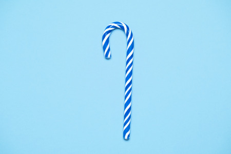 Striped blue and white candy cande on mint blue paper backgroundの写真素材