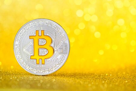 New shiny silver bitcoin coin with golder bitcoin B symbol on golden glitter background with copy spaceの写真素材