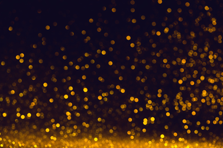 Abstract small golden bokeh lights on dark backgroundの写真素材