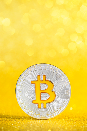 Bitcoin coin with golden bitcoin symbol on golden glitter bokeh backgroundの写真素材