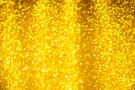 Gold glitter background. Shiny bright yellow christmas lighs bokeh.の写真素材