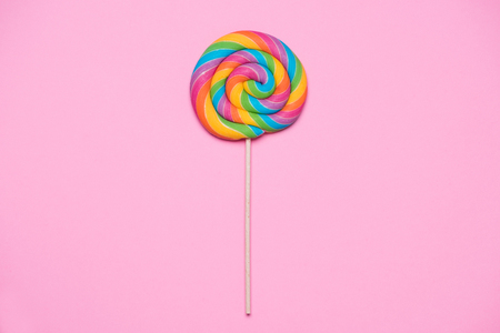 Lollipop swirl on wooden stick on pink paper backgroundの写真素材