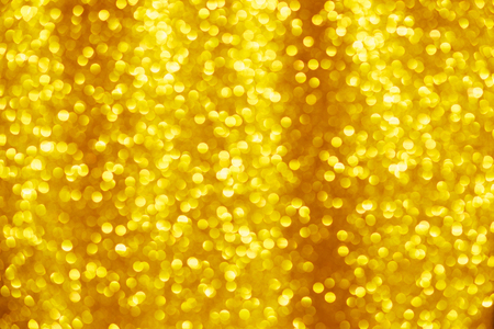 Gold glitter background. Shiny yellow christmas lighs bokeh.の写真素材