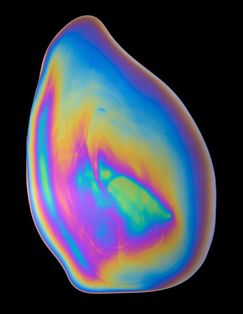 Uniq rainbow vivid oil film spill isolated on black backgroundの写真素材
