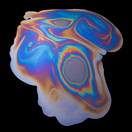 Abstract vivid rainbow iridescent oil spill on black backgroundの写真素材