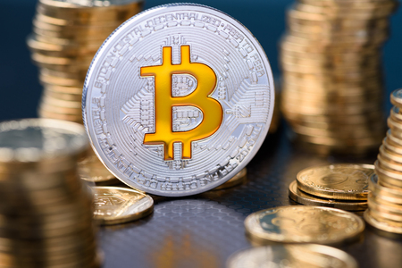 Bitcoin. Silver bitcoin coin between golden coins stacks with reflection.の写真素材