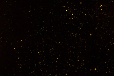 Tiny gold glitter falling on black backgroundの写真素材