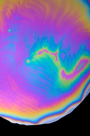 Abstract rainbow multicolored iridescent oil spill on black backgroundの写真素材