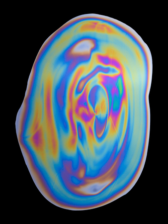 Abstract iridescent oil spill photograph on black backgroundの写真素材