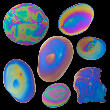 Set of iridescent oil drops spills isolated on black backgroundの写真素材