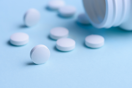 White round pills and pill bottle on blue backgroundの写真素材