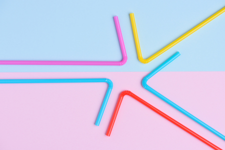 Colorful cocktail straws flat lay on blue and pink soft trendy pastel colored paper background with side copy spaceの写真素材