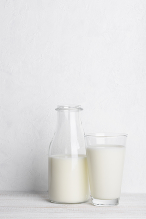 Bottle ang glass of milk on white wooden table background vertical with copy spaceの写真素材