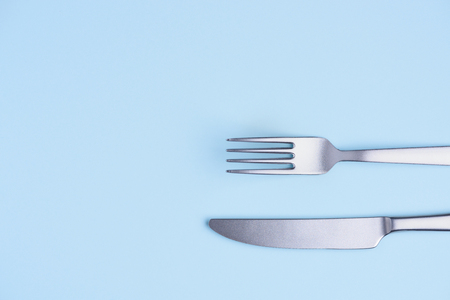 Knife and fork on blue pastel background flay layの写真素材