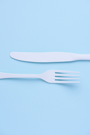 Clean new white knife and fork creative flat lay on trendy soft blue paper backgroundの写真素材