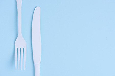 White new clean knife and fork flat lay on blue trendy pastel background with copy spaceの写真素材