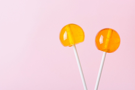 Two lollipops on white plastic sticks on pink pastel background with copy spaceの写真素材