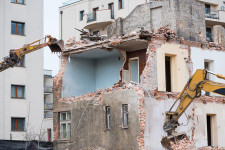 Old residential three story building demolition with hydraulic excavators