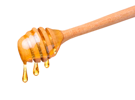 Honey drops dripping from wooden dipper spoon isolated on white backgroundの写真素材