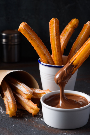 Churro with sugar powder and cinnamon in melted chocolate dipの写真素材