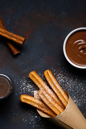 Traditional chrurro sticks hot with chocolate sausce and cinnamon flat lay copy spaceの写真素材