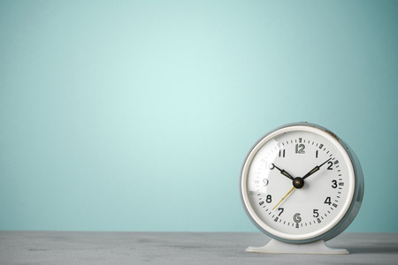 Retro old classic round alarm clock on desk blue vintage color background with copy spaceの写真素材