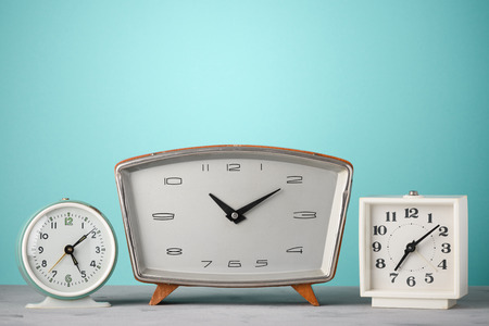 Retro clocks in a row on a table with blue background time conceptの写真素材