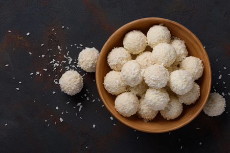 Coconut candies bowl on dark table background flat lay top viewの写真素材
