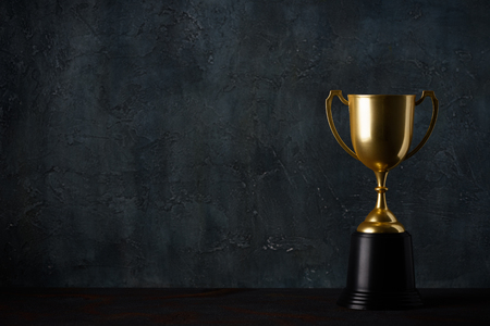 Golden trophy cup on table dark background with copy spaceの写真素材