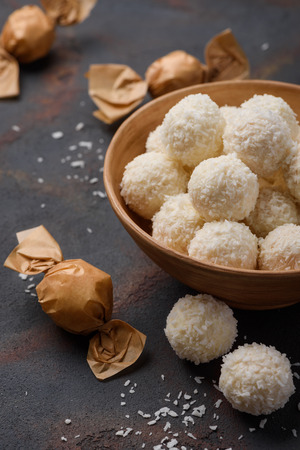 Coconut candy in bowl and wrapped in paper on dark table backgroundの写真素材
