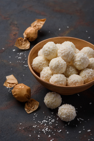 Coconut candies in bowl and wrapped on dark table backgroundの写真素材
