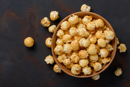 Caramel popcorn in bowl on dark table backgroundの写真素材